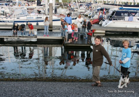 Op de steigers van de Waddenhaven in Oudeschild geniet de jeugd van het mooie weer en krabben vissen.