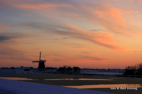 De kleurige zonsondergang bij de molen 't Noorden nabij Oost kondigt strenge vorst aan voor de nacht van zondag op maandag.